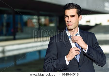 Young Handsome Businessman Adjusting A Tie In Urban Background