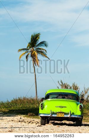 Havana, Cuba 2008.01.24 Neon-green car parked under a palm tree on the beach