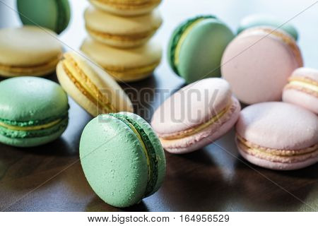 Freshly made pink, green and yellow french macarons on the tabke
