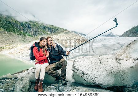 Young Couple Hiking in the Swiss Alps, Taking a Selfie. This is a generic, low-cost camera and not the 'famous original' brand.