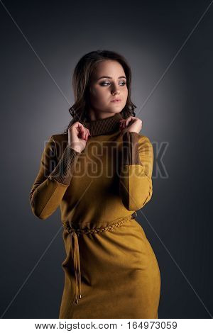 Sexy slim long haired girl poses in studio in slinky mustard dress