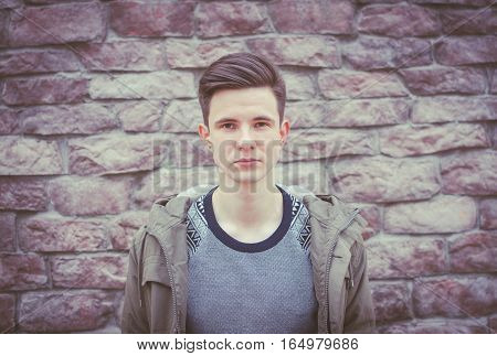 Young beautiful seriosly man on the city brick wall background