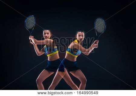 Portrait of beautiful girl tennis player with a racket on dark studio background. Stroboscope shooting technique