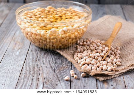 Chickpeas soaked in water in a bowl on wooden background