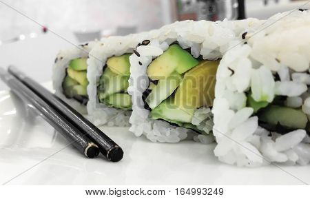 Japanese cuisine. Closeup of fresh veggie maki rolls with avocado.
