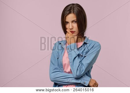 A Pretty Thoughtful Young Caucasian Woman Holding Her Chin Looks Seriously And Tries To Gather Her T