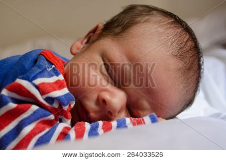 Two Weeks Old Newborn Baby Boy Sleeping In Blu Red Pijama