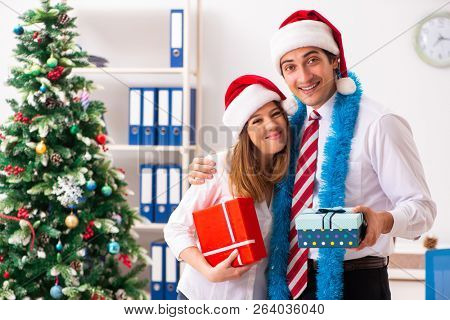 Colleagues exchaing christmas presents in office