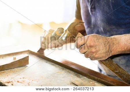 Closeup Of A Carpenter Hands Working With A Chisel And Hammer On Wooden Workbench