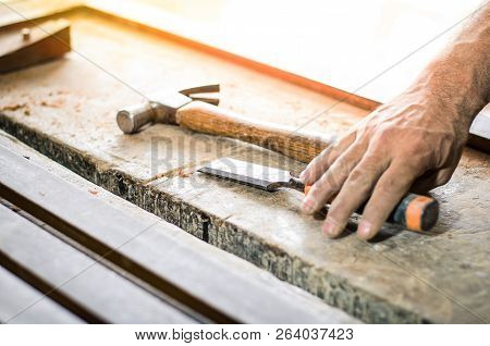 Closeup Of A Carpenter Hands Working With A Chisel And Hammer On Wooden Workbench