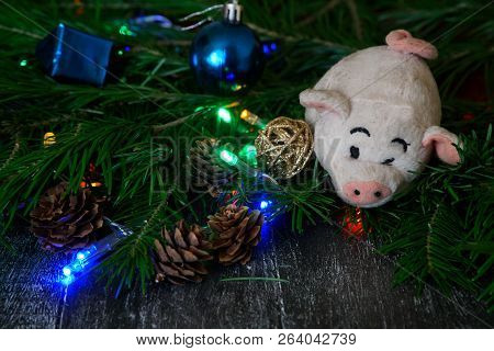 Vintage Plush Pig - A Symbol Of The New Year Holidays Next To The Christmas Tree, Cones, Toys And Co