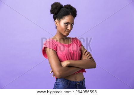 Photo Of Offended Or Naughty African American Woman Standing With Arms Folded Isolated Over Violet Background Photo Of Offended Or Naughty African American Woman Standing With Arms Folded Isolated Over Violet Background