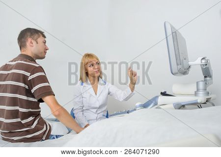 The Lady Ultrasunography Doctor Is Explaining To The Patientat Divice, In Medical Office