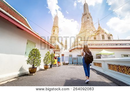 Tourist Women With Carrying A Backpack Viewing Poster, About The Temple In Bangkok At Arunratchawara