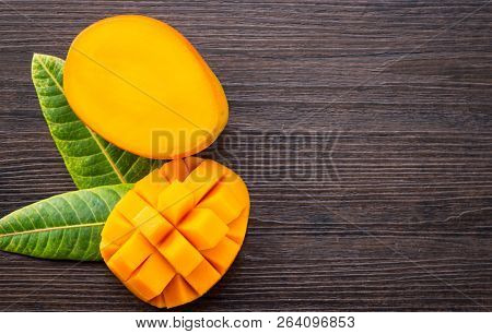 Fresh And Beautiful Mango Fruit With Sliced Diced Mango Chunks On A Dark Wooden Background, Copy Spa