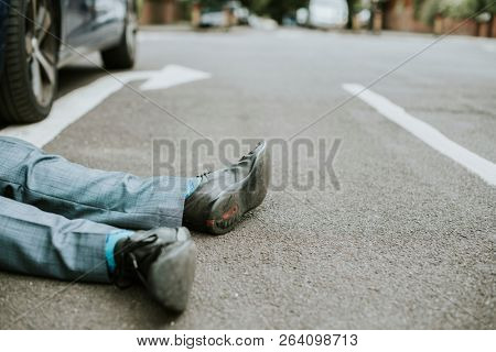 Person lying on the ground after a car accident