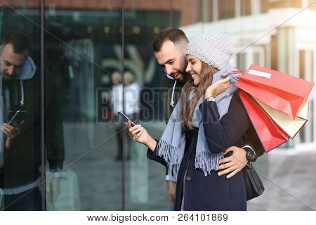 Portrait of happy couple with shopping bags after shopping in city