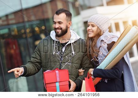 Portrait of happy couple with shopping bags after shopping in city