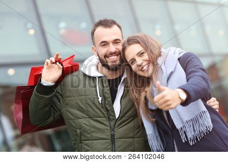 Portrait of happy couple with shopping bags after shopping in city