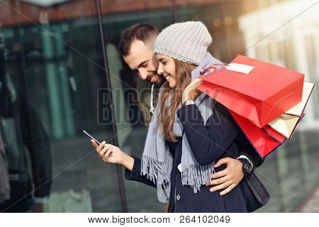 Portrait of happy couple with shopping bags after shopping in city