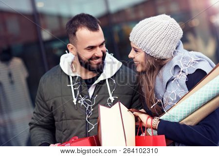 Portrait of happy couple with shopping bags after shopping in city