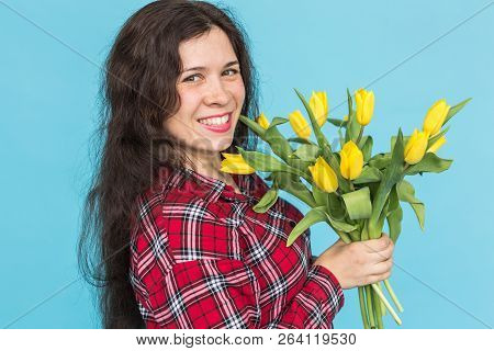 Laughing Young Caucasian Woman With Bouquet Of Tulips On Blue Background.