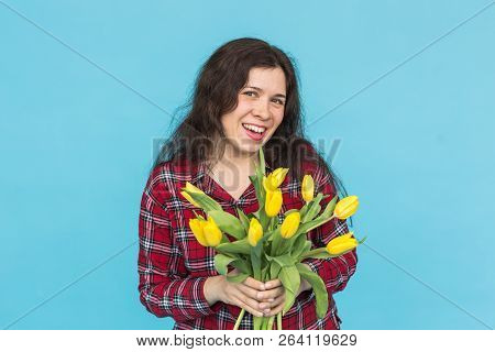 Laughing Young Caucasian Woman With Bouquet Of Tulips On Blue Background.