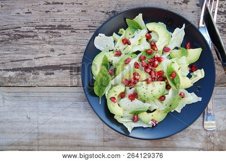 Vegetarian Salad With Avocado, Greens, Leaves, Pomegranate And Letuce Leaves. Wooden Rustic Table.