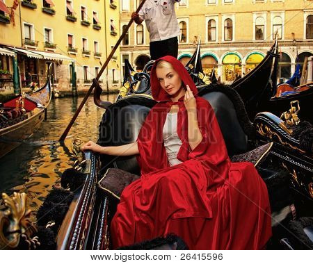 Bella donna in mantello rosso cavalcando gandola