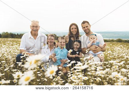 Family With Grandparent Spending Time With Little Child During The Sunset.