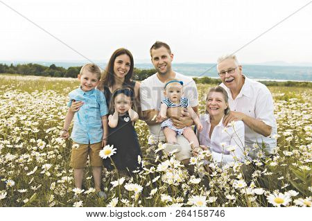 Family With Grandparent Spending Time With Little Child During The Sunset.