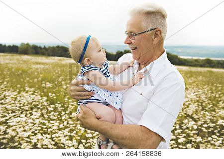 Grandfather Spending Time With Little Child During The Sunset.