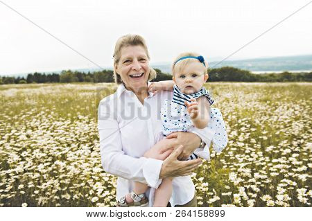 Grandmother Spending Time With Little Child During The Sunset.
