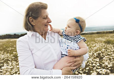 Grandmother Spending Time With Little Child During The Sunset.