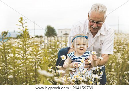 Grandfather Spending Time With Little Child During The Sunset.