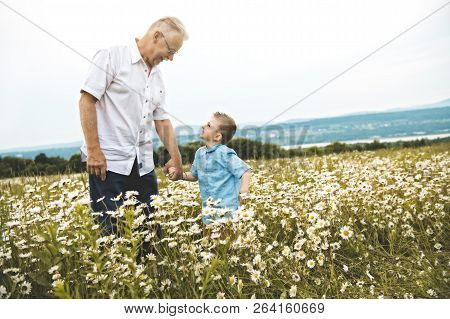 Grandfather Spending Time With Little Child During The Sunset.