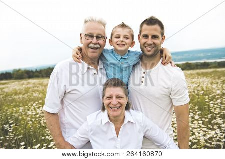 Grandfather Grandmother And Son Spending Time With Little Child During The Sunset.