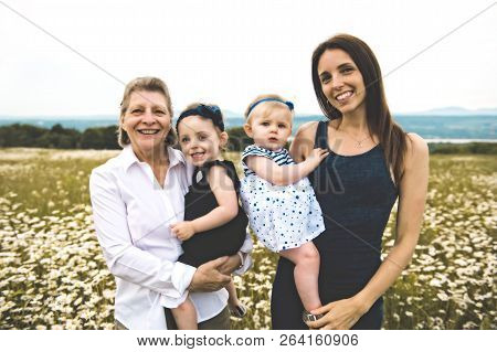 Grandmother And Mother Spending Time With Little Child During The Sunset.