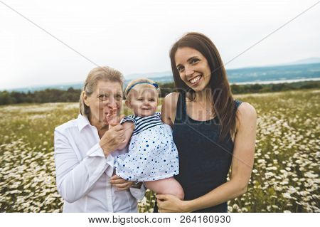 Grandmother And Mother Spending Time With Little Child During The Sunset.