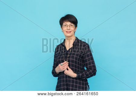 Mid-aged Woman With Short Hair Wearing Glasses And Shirt Standing Against Blue Background With Copy 