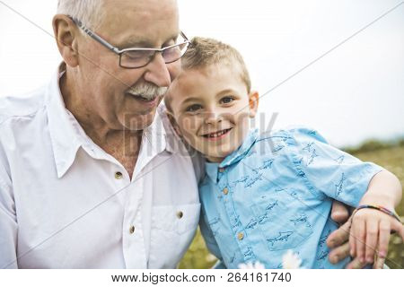 Grandfather Spending Time With Little Child During The Sunset.
