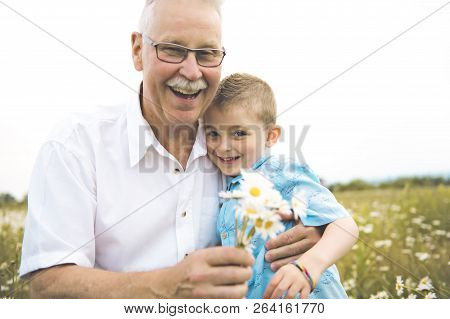 Grandfather Spending Time With Little Child During The Sunset.