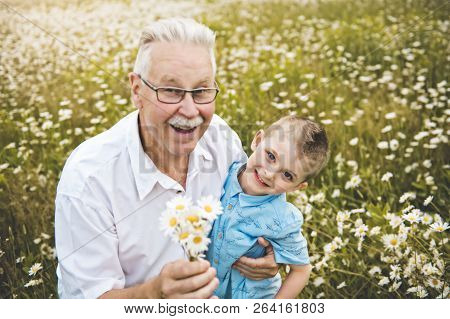 Grandfather Spending Time With Little Child During The Sunset.