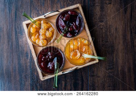 Various Glass Bowl Of Fruit Jams Apricot, Cherry, Strawberry, Damson Plum In Wooden Tray.