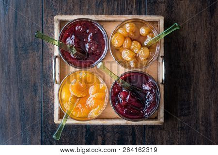 Various Glass Bowl Of Fruit Jams Apricot, Cherry, Strawberry, Damson Plum In Wooden Tray.