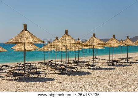 Umbrellas On The Borsh Beach In Albania. Stony Beach On The Adriatic Sea.