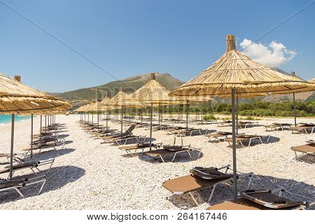 Umbrellas On The Borsh Beach In Albania. Stony Beach On The Adriatic Sea.
