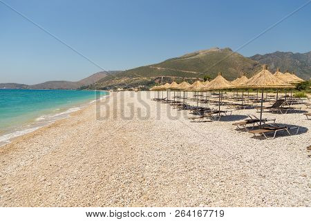 Umbrellas On The Borsh Beach In Albania. Stony Beach On The Adriatic Sea.