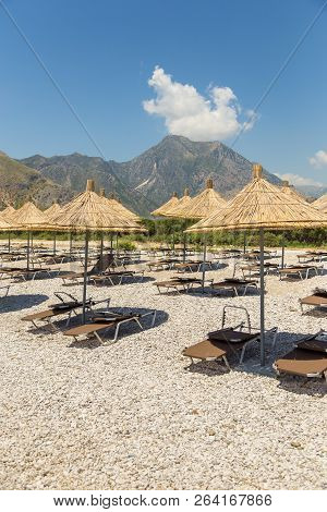 Umbrellas On The Borsh Beach In Albania. Stony Beach On The Adriatic Sea.