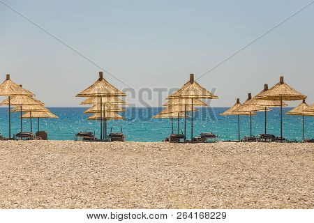 Umbrellas On The Borsh Beach In Albania. Stony Beach On The Adriatic Sea.